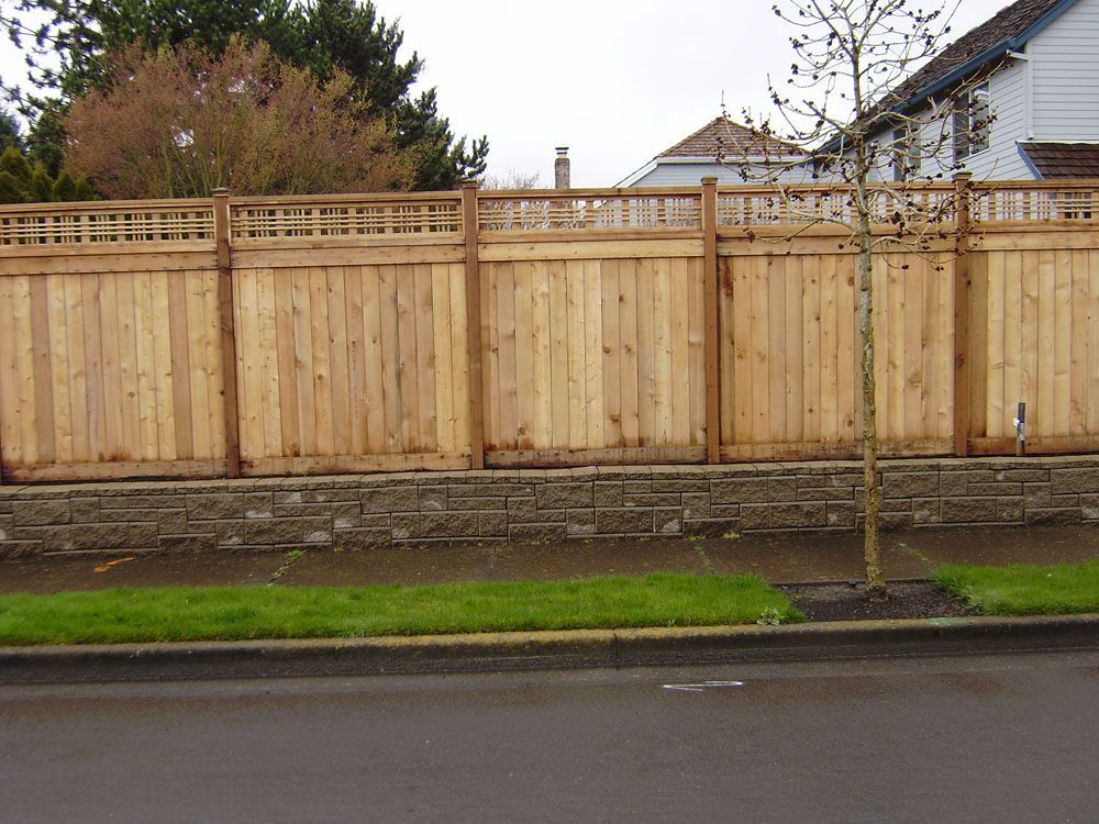 A wooden fence with a stone wall behind it