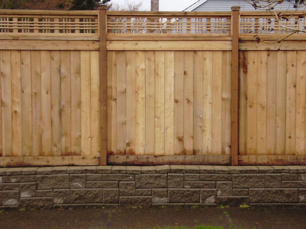 A wooden fence with a stone wall behind it