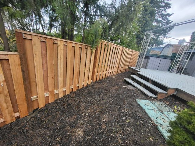 A wooden fence surrounds a deck in a backyard