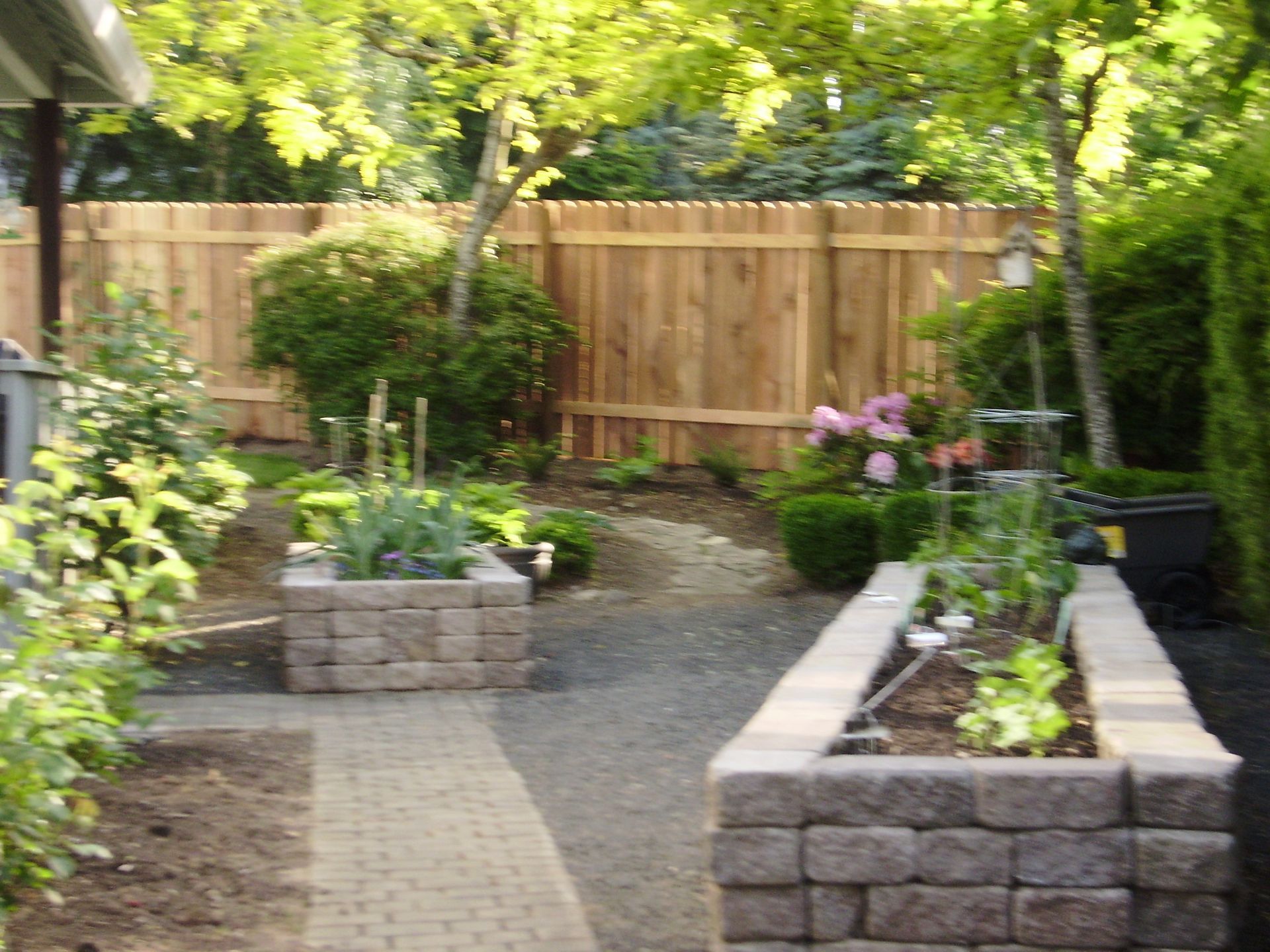 A garden with a wooden fence and brick planters