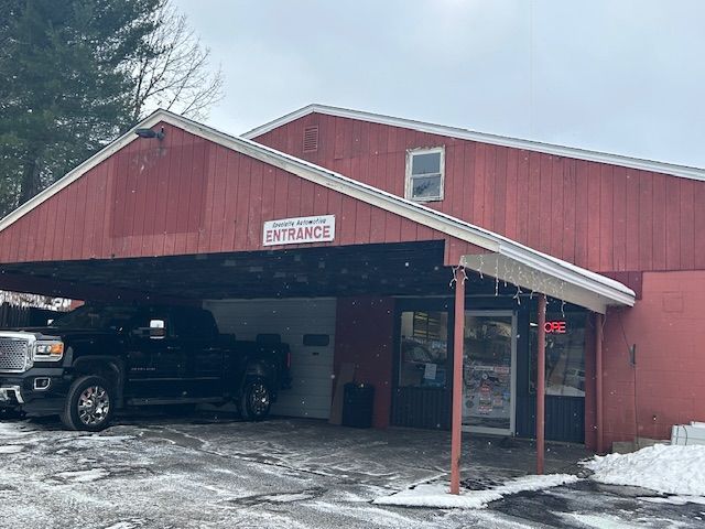 A red barn with a truck parked in front of it.