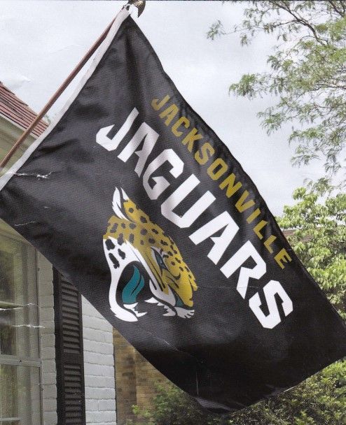 A jacksonville jaguars flag is flying in front of a house