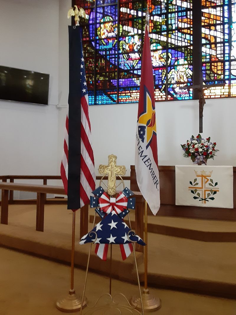 A stained glass window in a church with flags in front of it