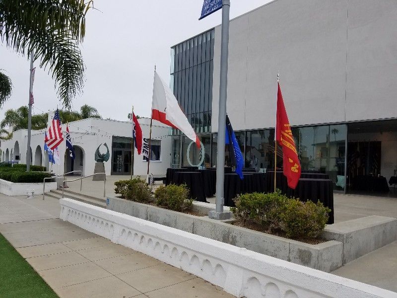 A group of flags are flying in front of a building.