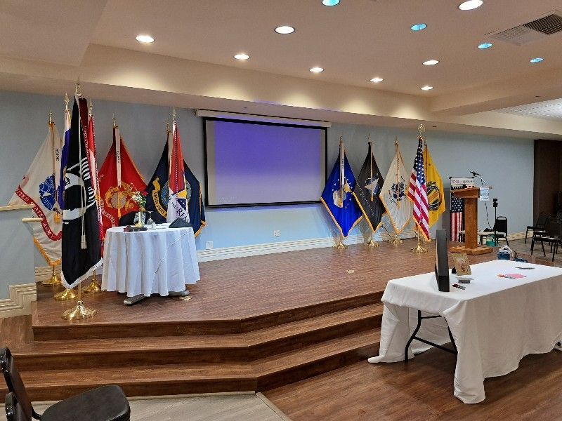 A large room with a stage and flags on it.