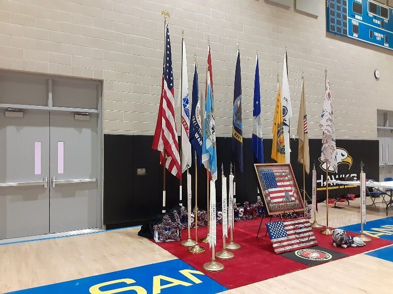 A row of american flags are lined up in a gym.