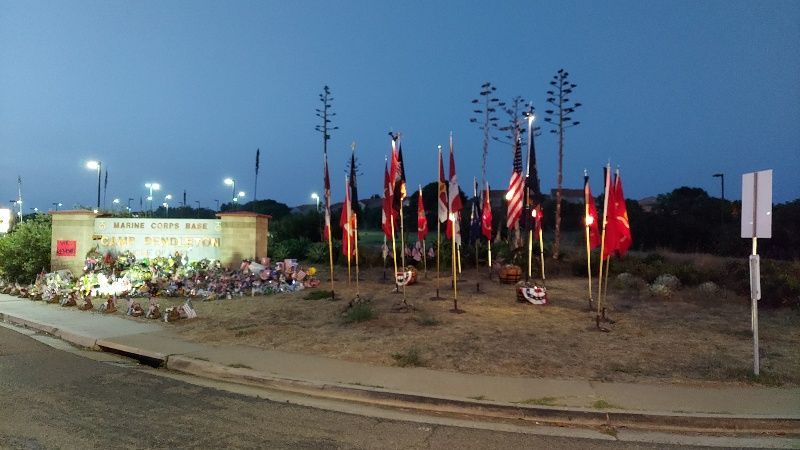 A bunch of flags are lined up in a circle in front of a sign.