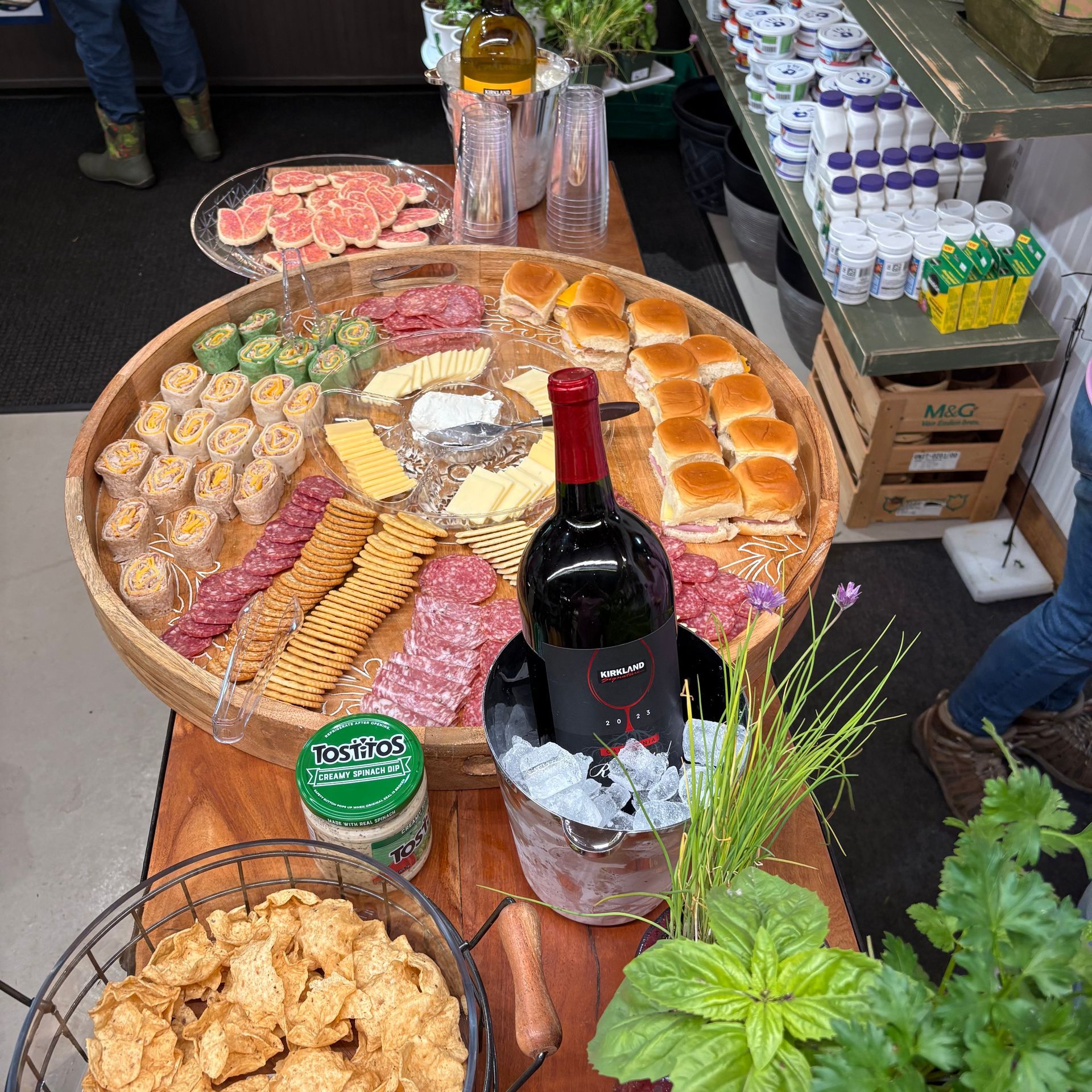 Market table with assorted breads, pastries, olives, and a bottle of wine on display