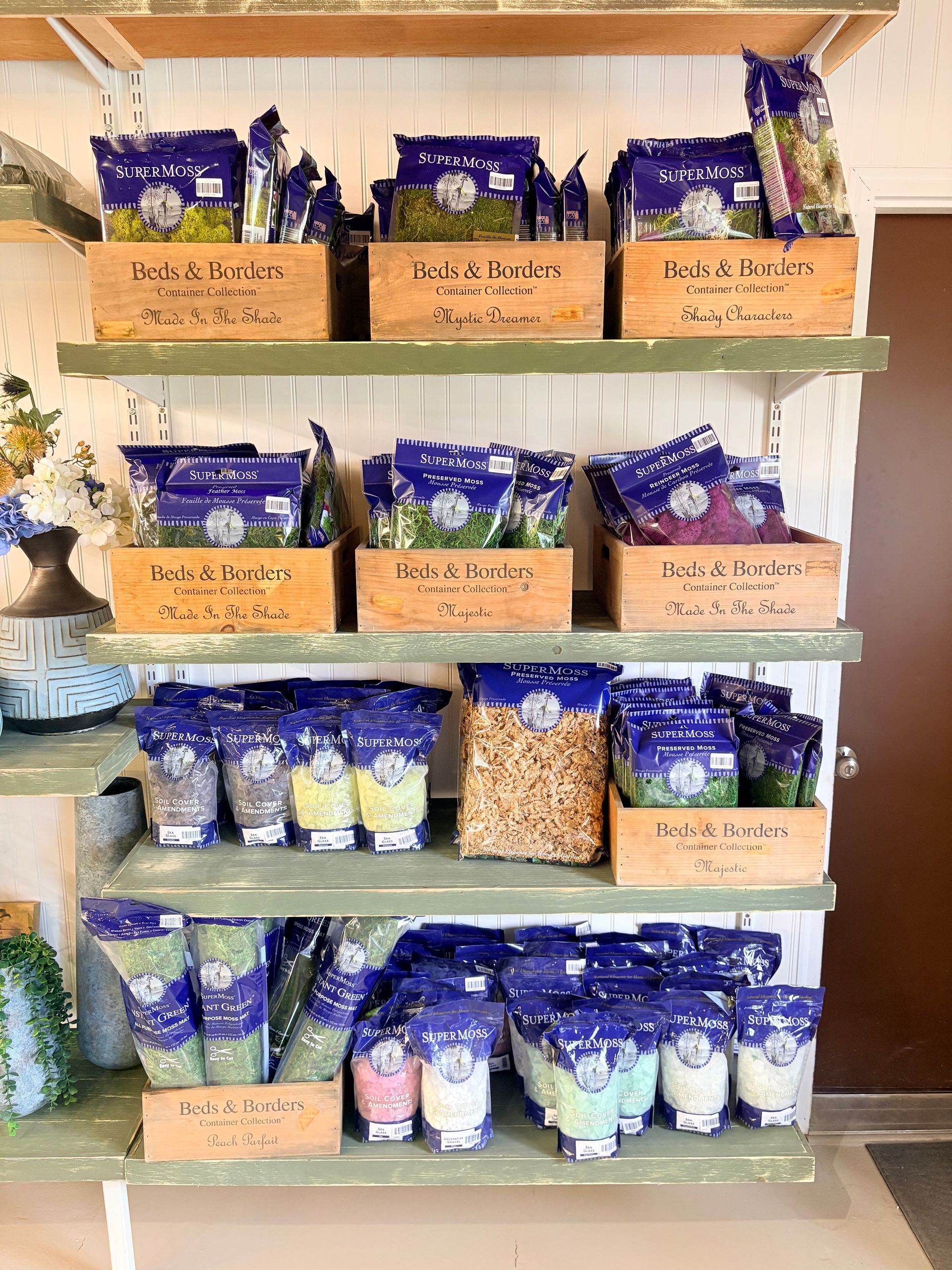 Shelves of purple and white packaged goods in brown bins, displayed in a market or shop aisle.