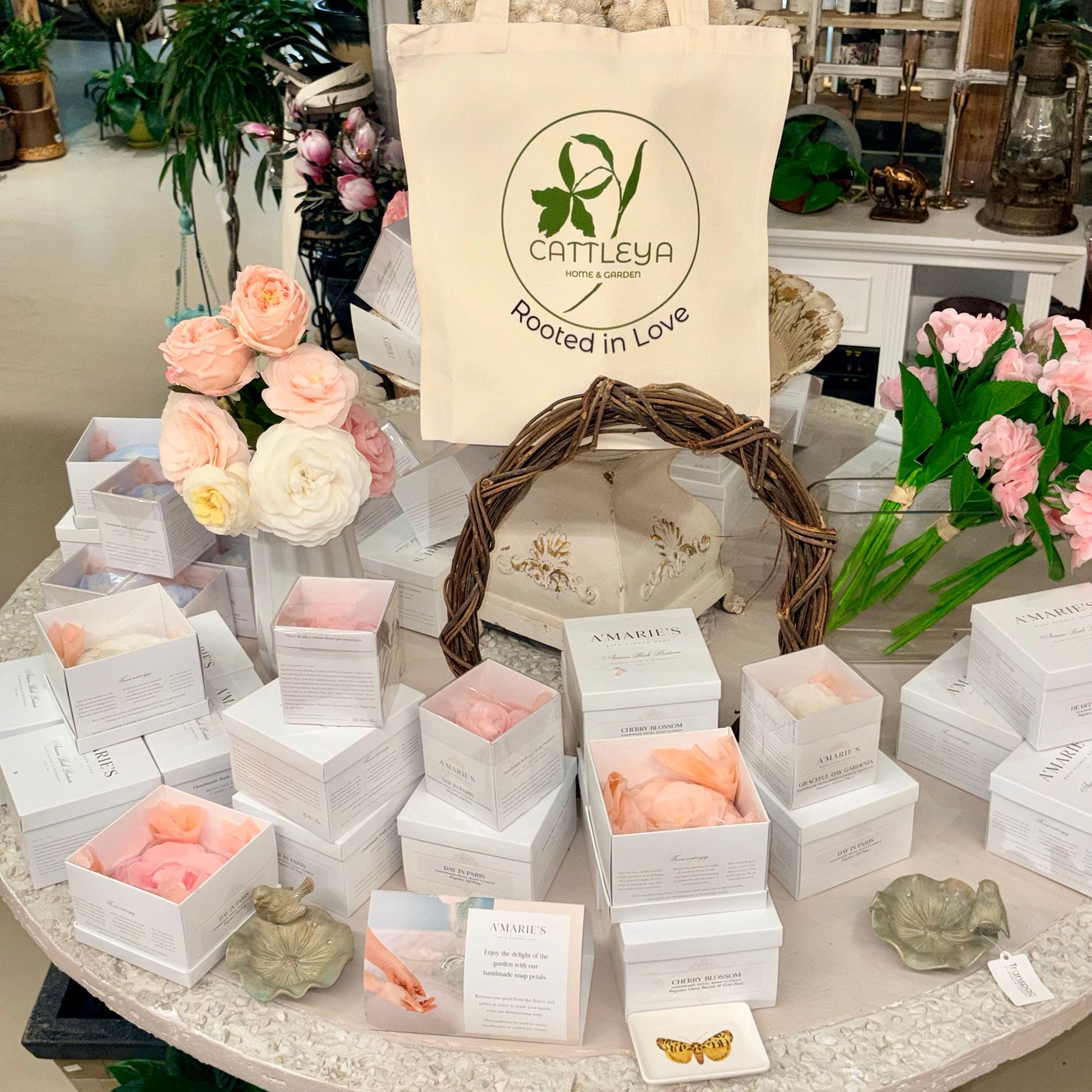 Assorted pastel gift boxes and flowers on a table with a branded paper bag centerpiece