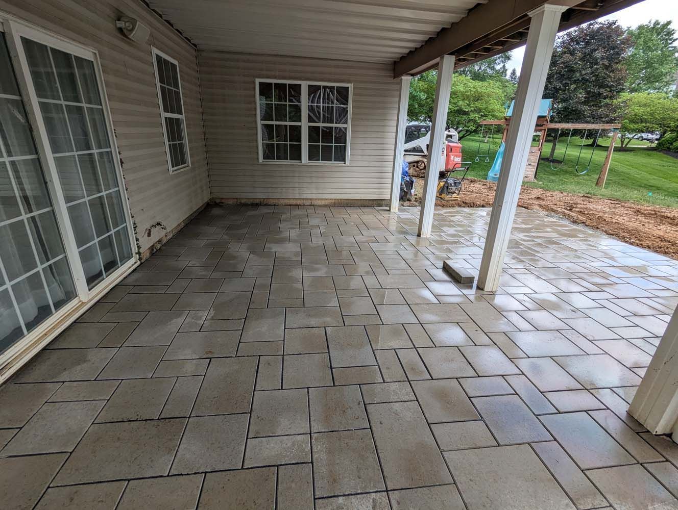 Brick pathway with drainage grate, brown gravel border, and green grass on either side.