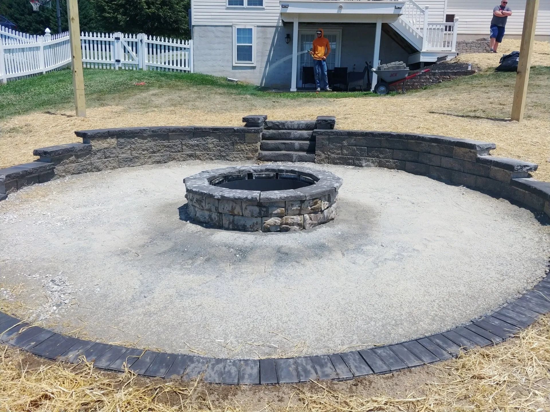 Circular fire pit area with stone walls, stairs, and gravel base. Person in background.
