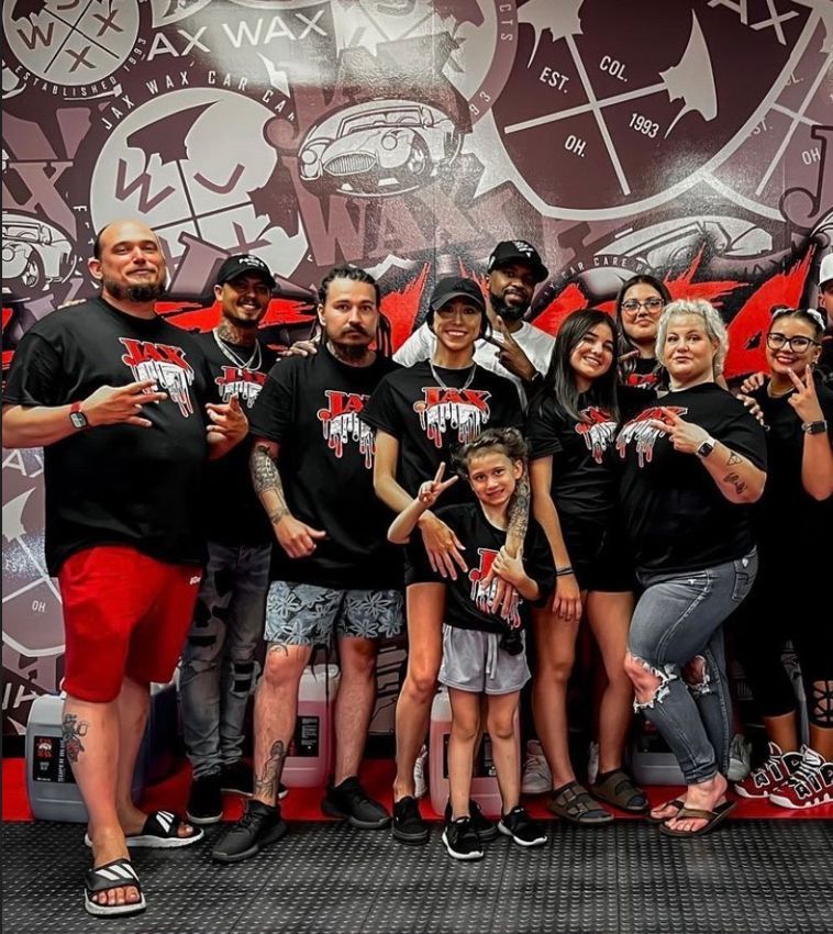 Group of people wearing matching shirts pose in front of a wall graphic.