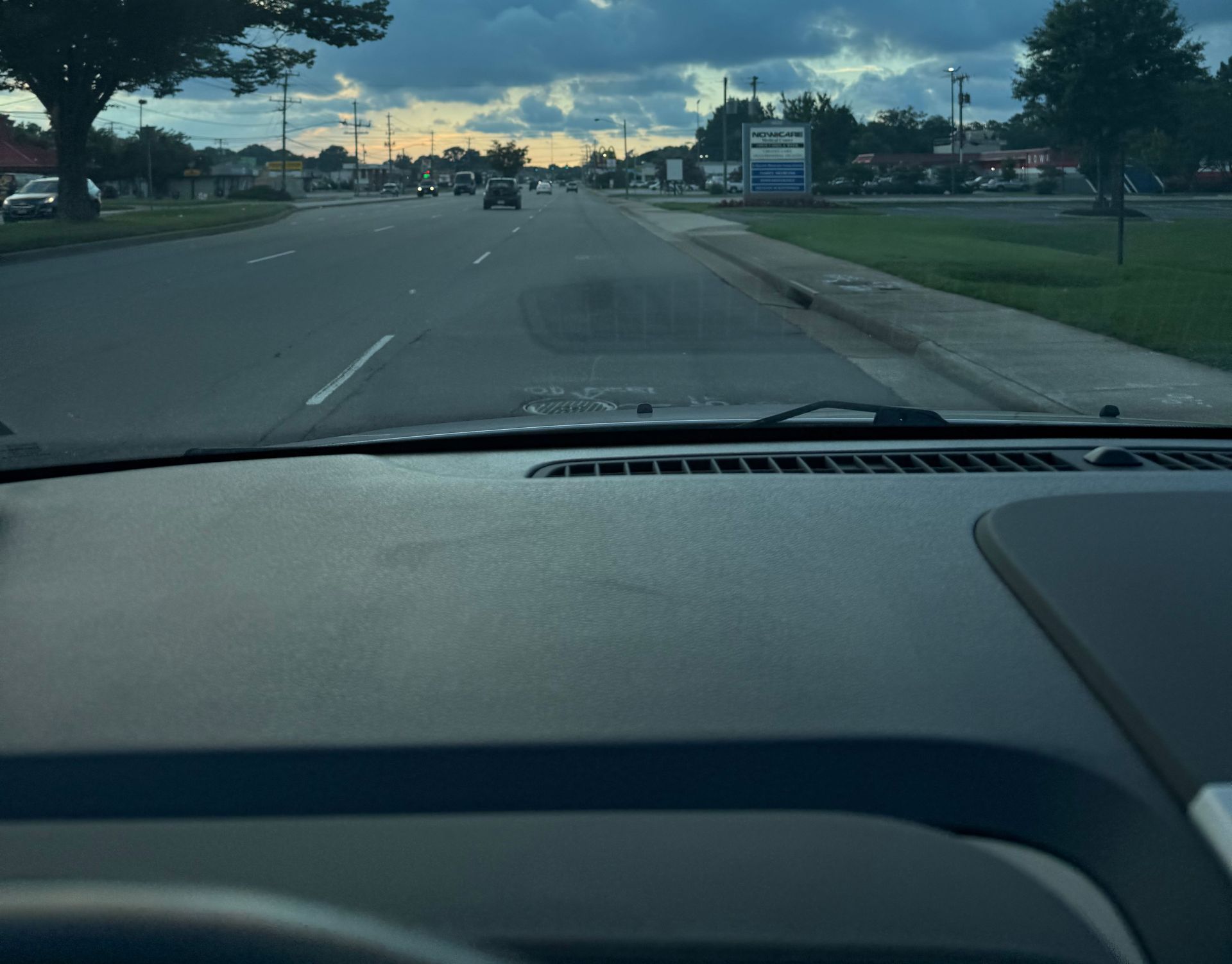 View from inside a car driving on a road under a cloudy sky.
