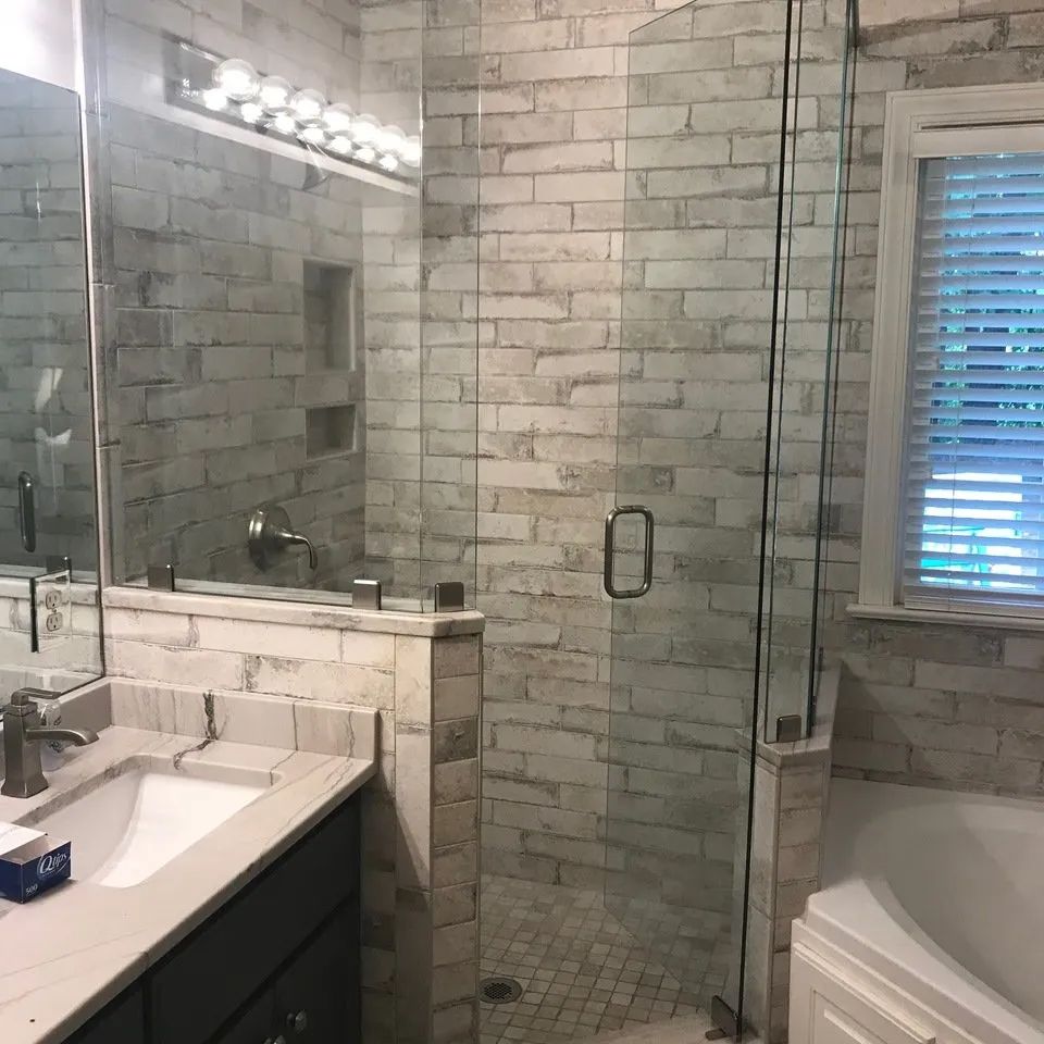 A bathroom with a walk in shower , sink , tub and mirror.