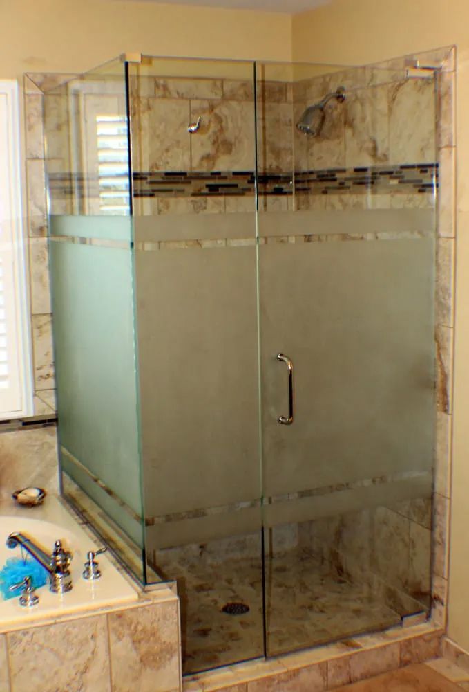 A bathroom with a walk in shower with a frosted glass door.
