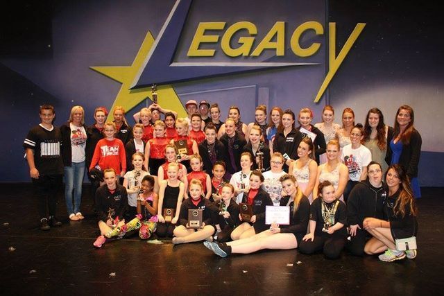 A group of people are posing for a picture in front of a sign that says legacy