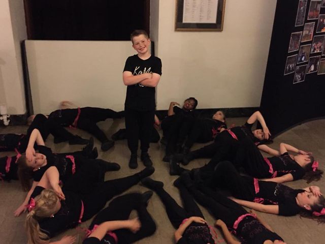 A boy stands in front of a group of children laying on the floor
