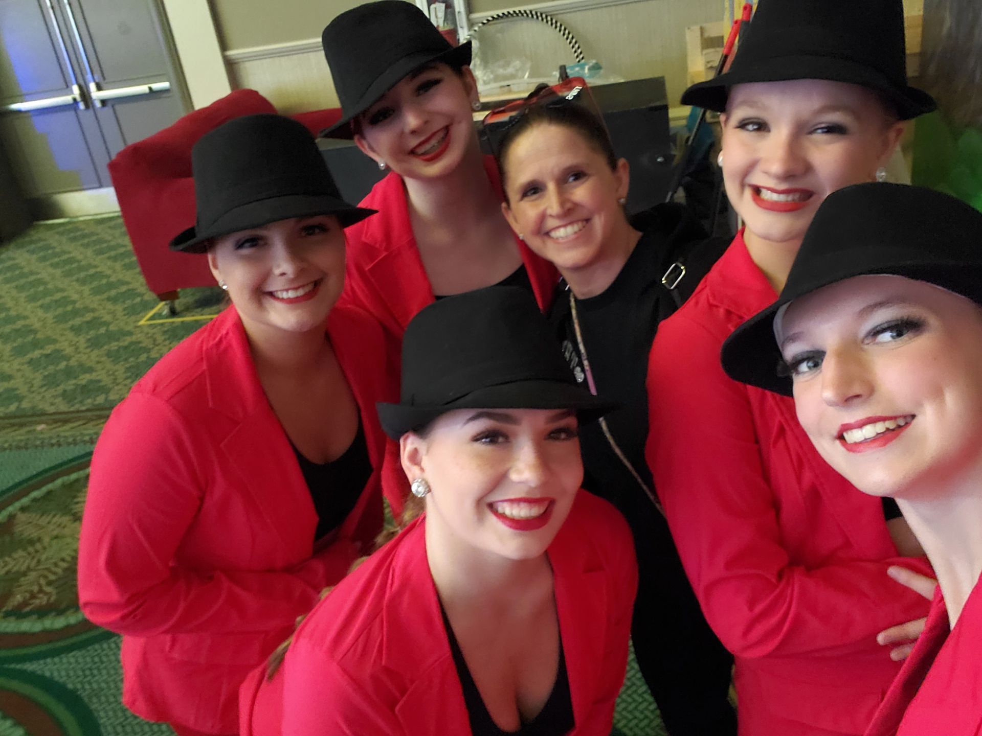 A group of women wearing red jackets and black hats are posing for a picture
