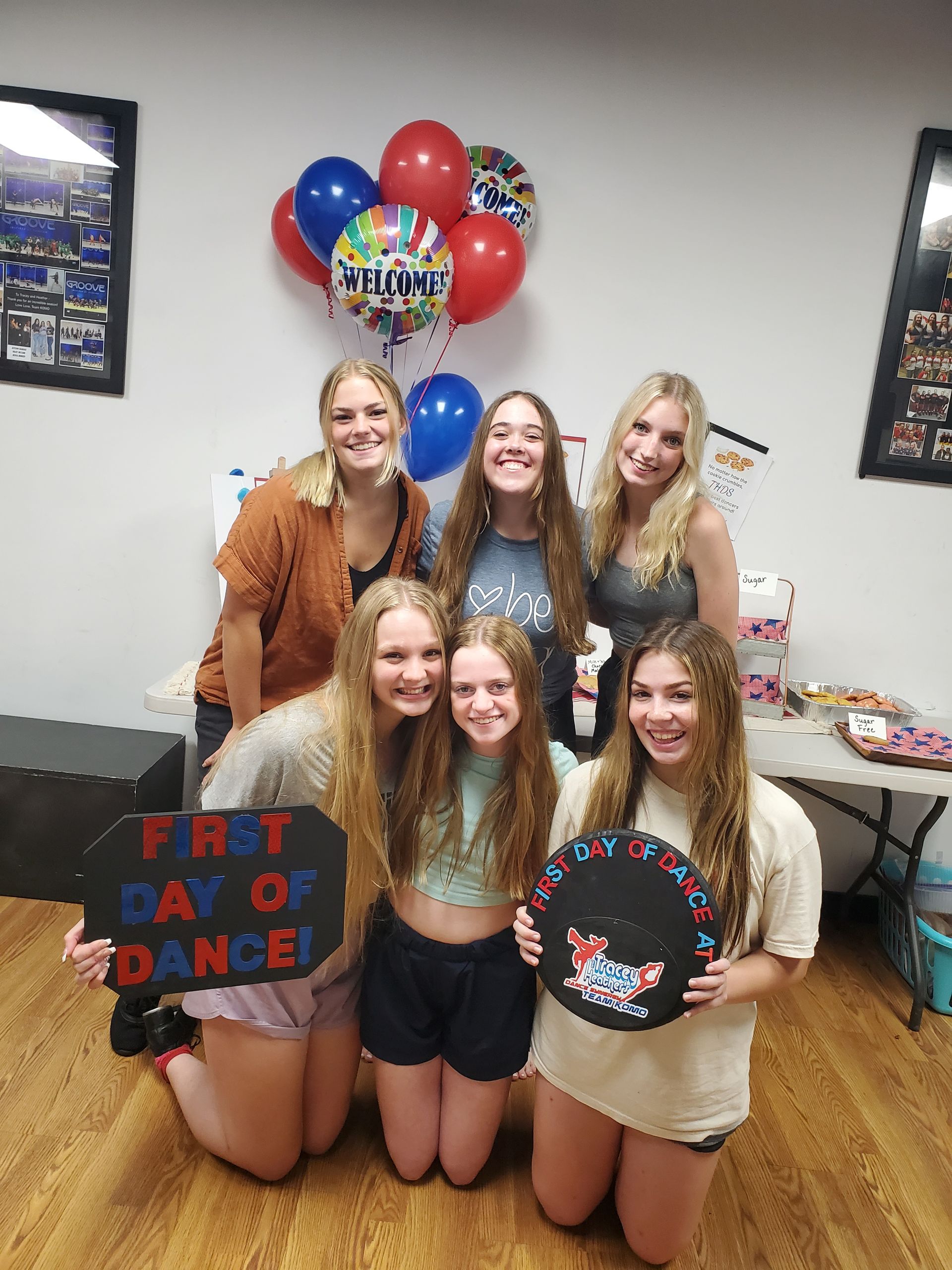 A group of young women are posing for a picture in a room with balloons.