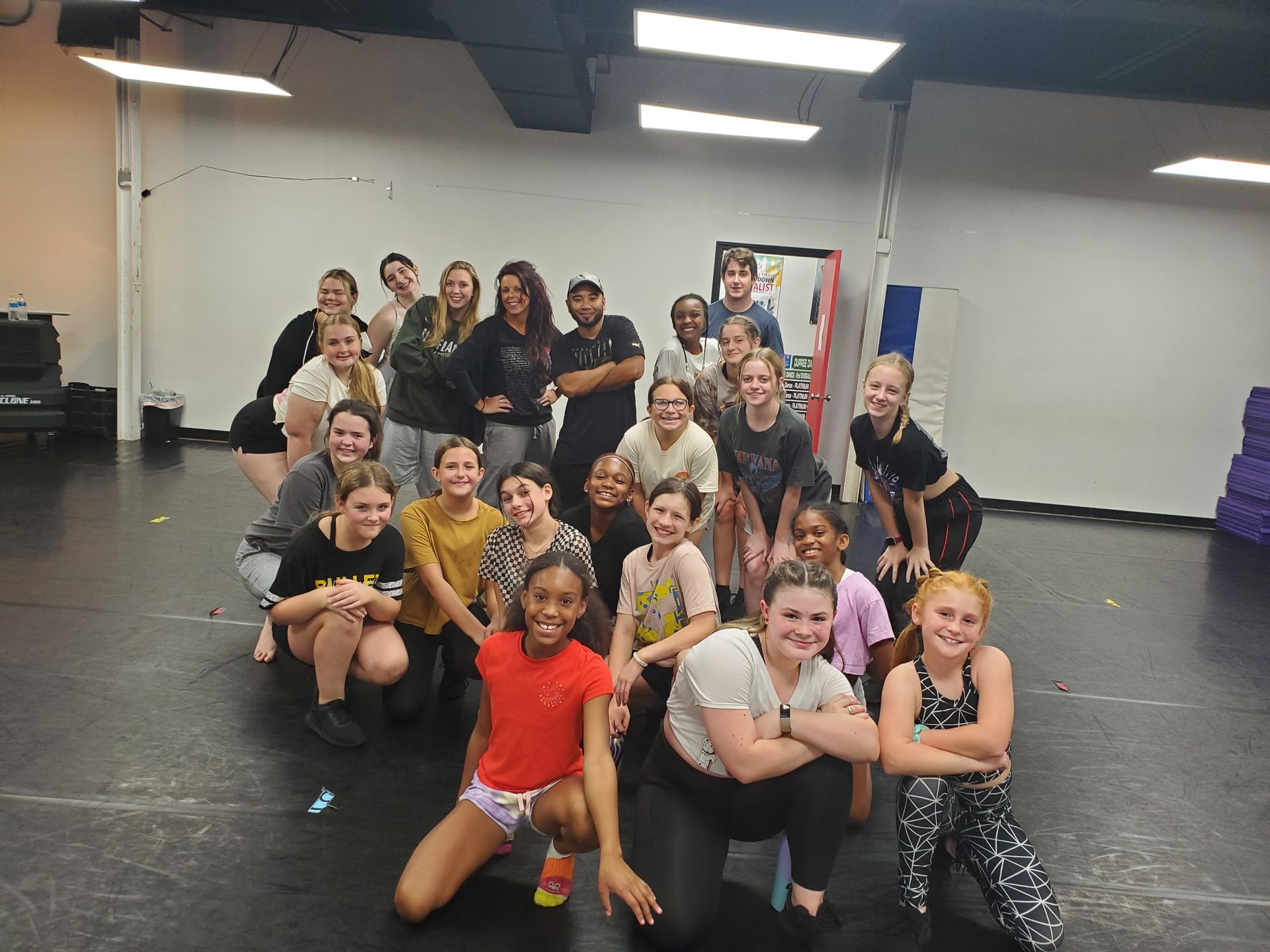 A group of young people are posing for a picture in a dance studio.