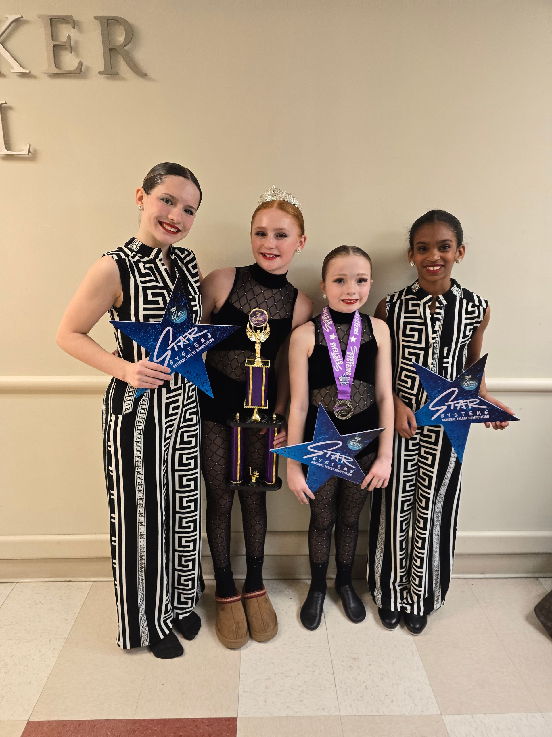 A group of young girls standing next to each other holding trophies