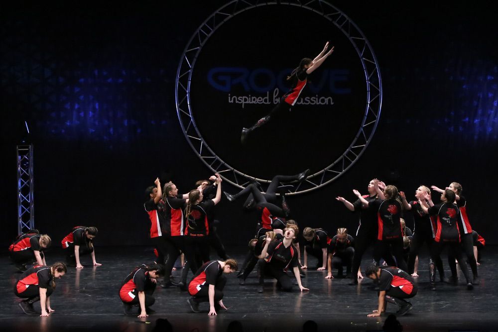 A group of people are performing on a stage with a hoop in the background.