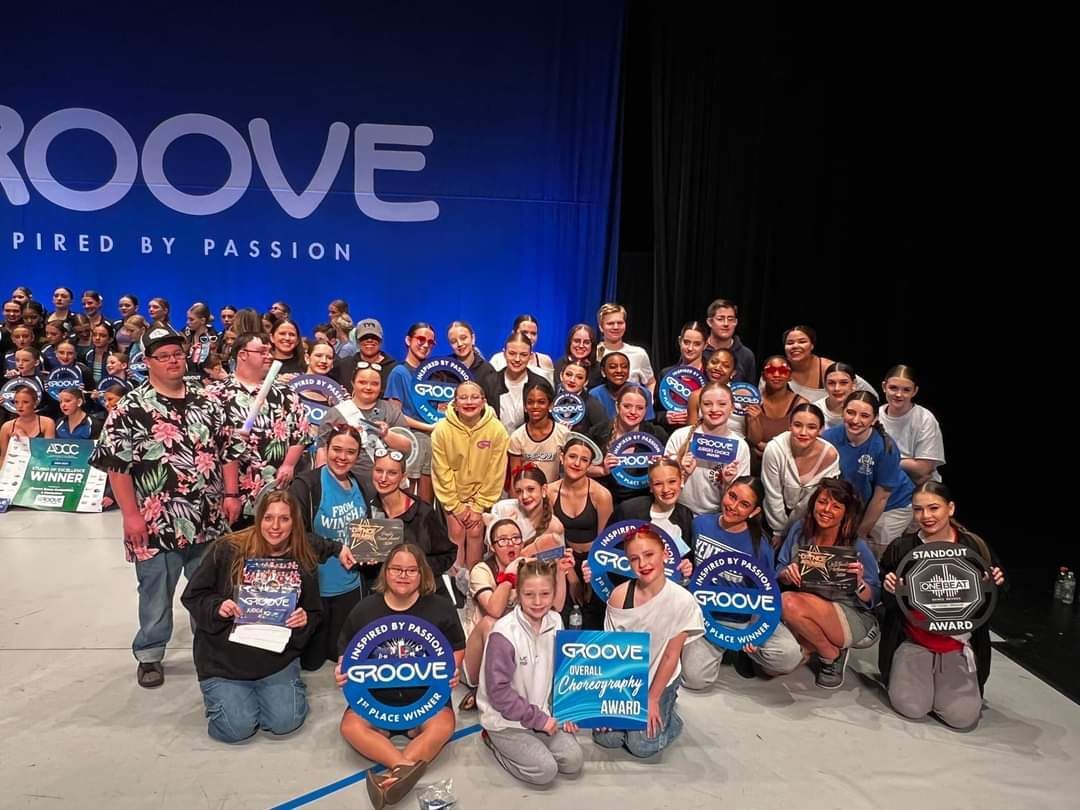 A large group of people are posing for a picture in front of a sign that says groove.