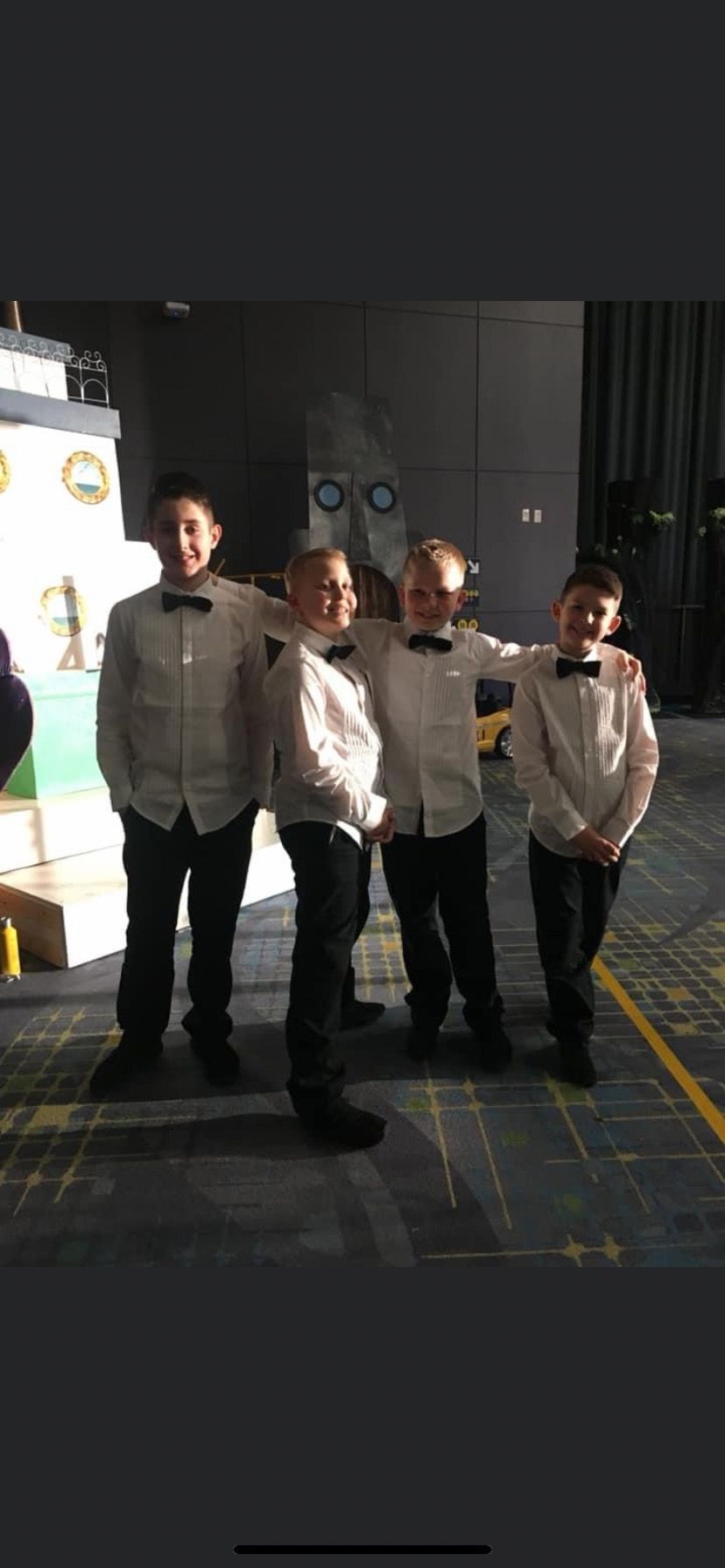 A group of young boys in tuxedos are posing for a picture.