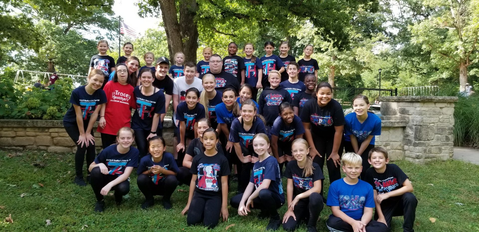 A group of young people are posing for a picture in a park.