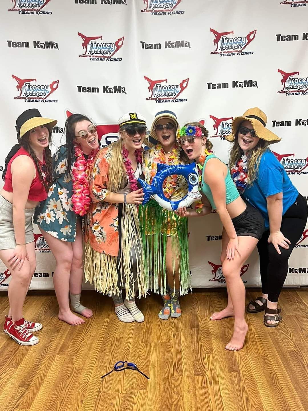 A group of women are posing for a picture in front of a wall.