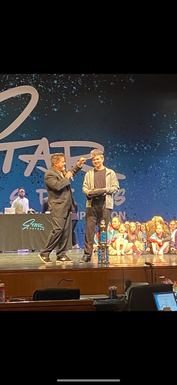 Two men are dancing on a stage in front of a crowd.