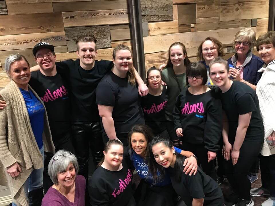 A group of people posing for a picture in front of a wooden wall.
