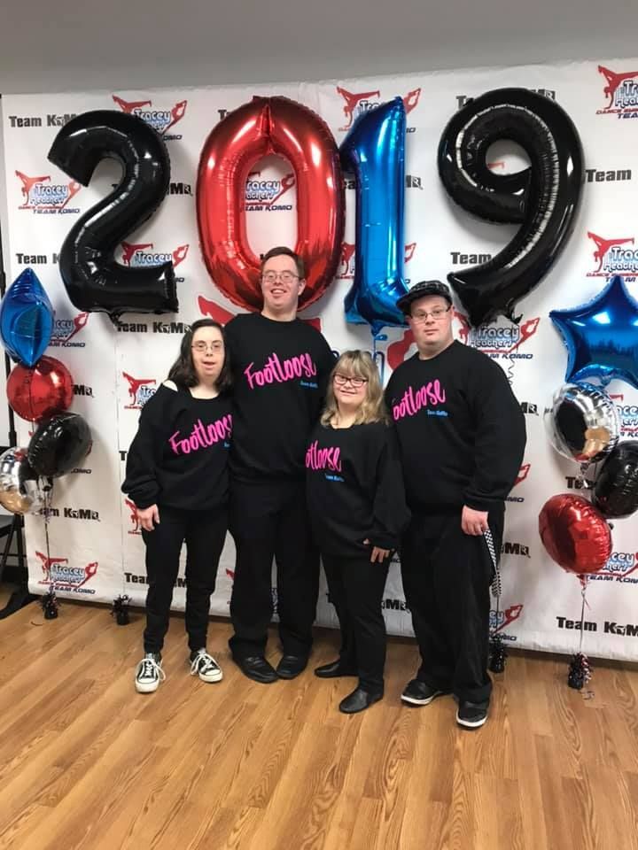 A group of people standing in front of a wall with balloons and a sign that says 2019.