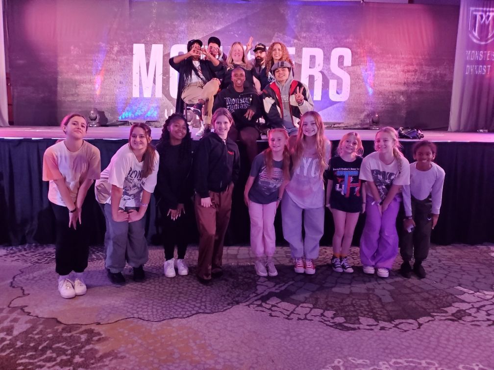 A group of young people are posing for a picture in front of a stage.