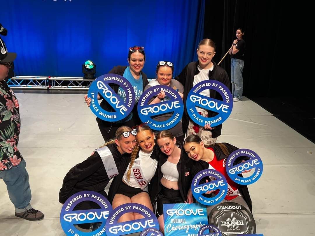 A group of young women are posing for a picture on a stage.