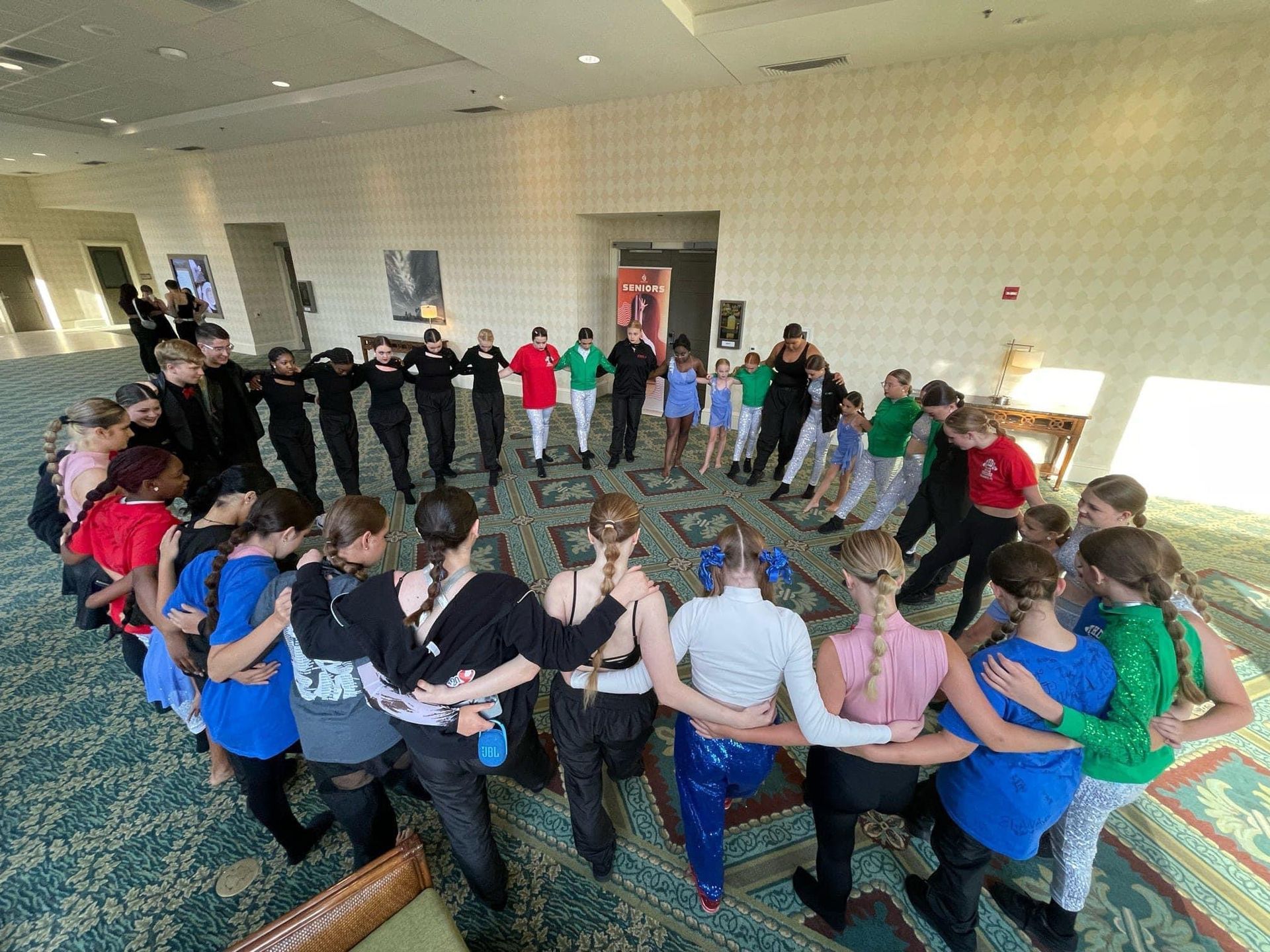 A group of people are standing in a circle with their arms around each other.
