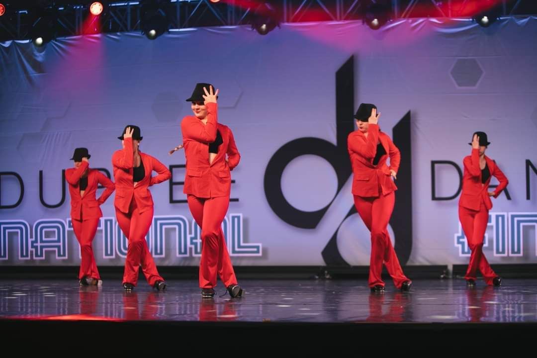 A group of people are dancing in front of a sign that says national dance