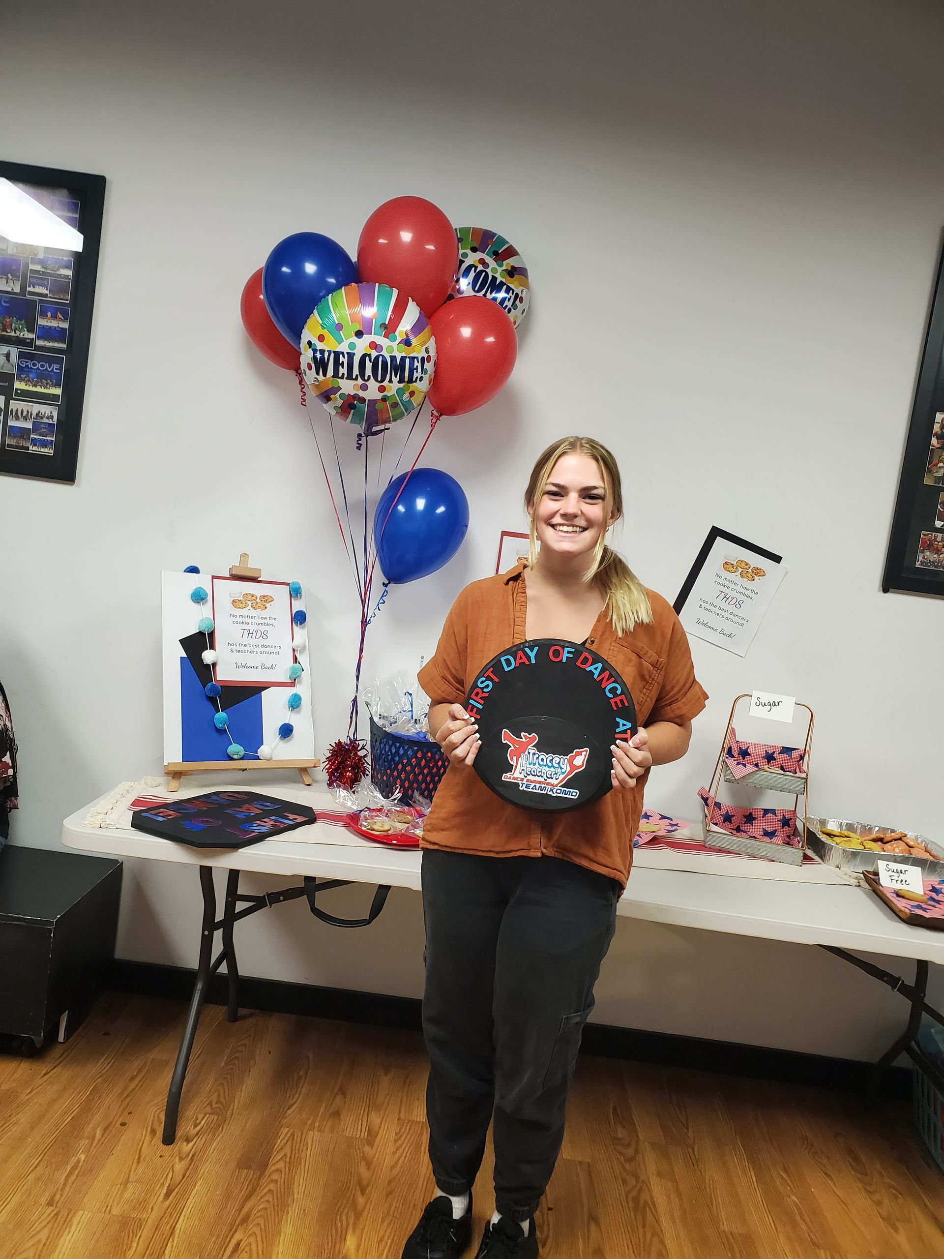 A woman is holding a plate in front of a table with balloons.