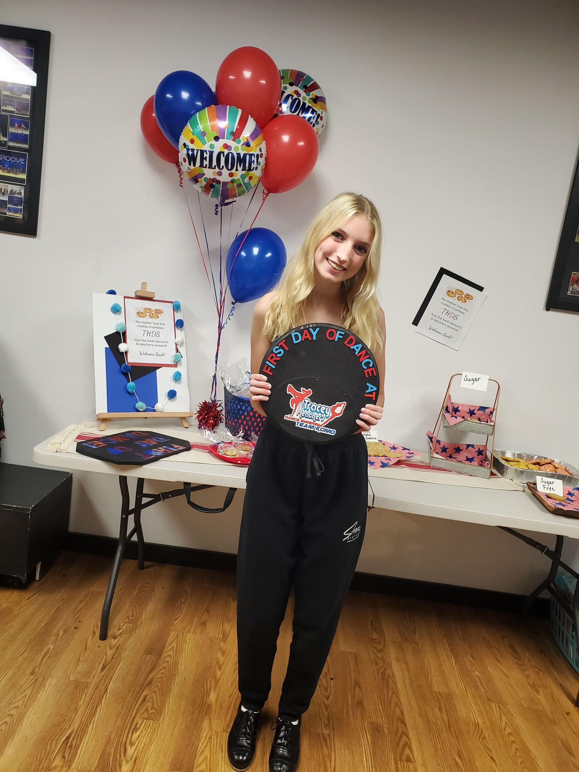 A woman is standing in front of a table with balloons and holding a plate.