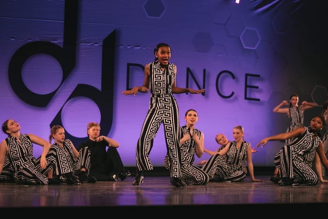 A group of dancers are performing in front of a sign that says dance