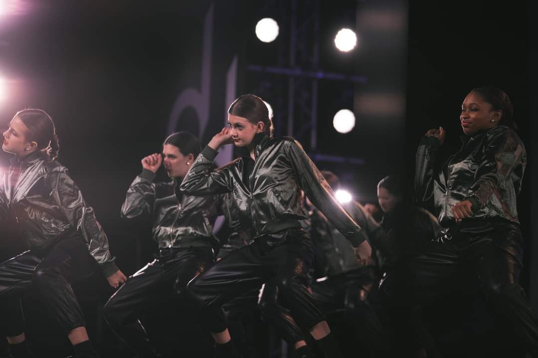 A group of people are dancing on a stage in a dark room.
