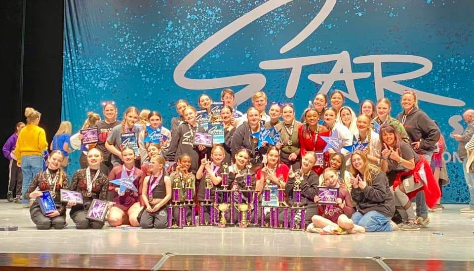 A group of young girls are posing for a picture on a stage.