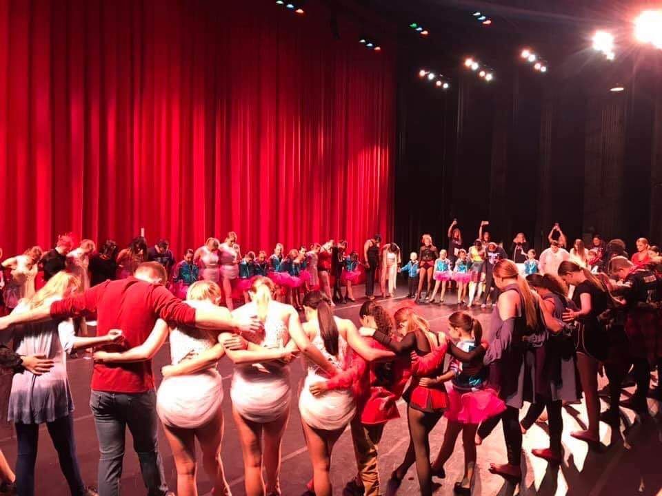 A group of people are standing on a stage with their arms around each other.