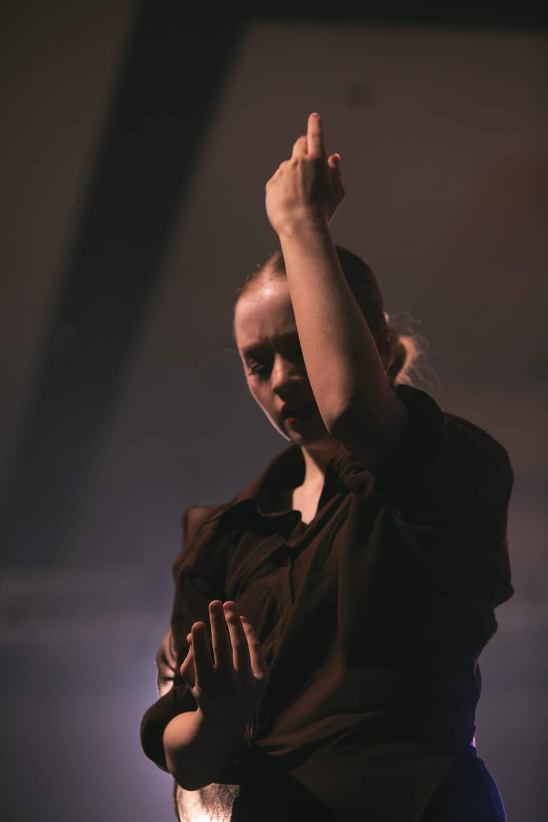 A woman in a black shirt is holding her hand up in the air.