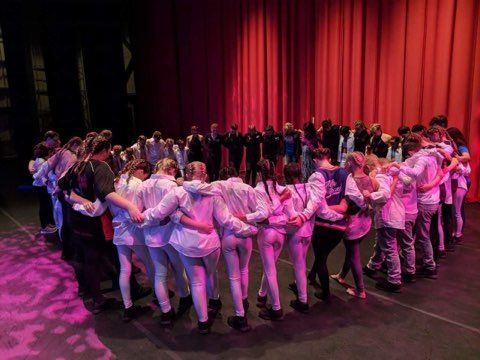 A group of people are standing in a circle on a stage.