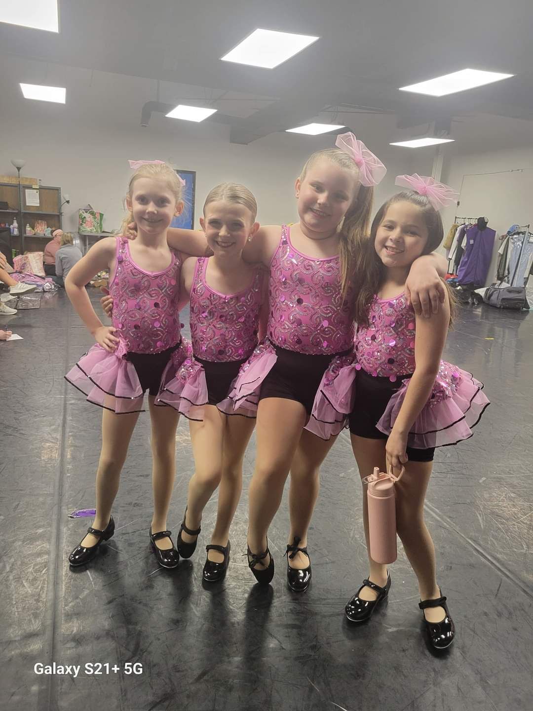 A group of young girls are posing for a picture in a dance studio.