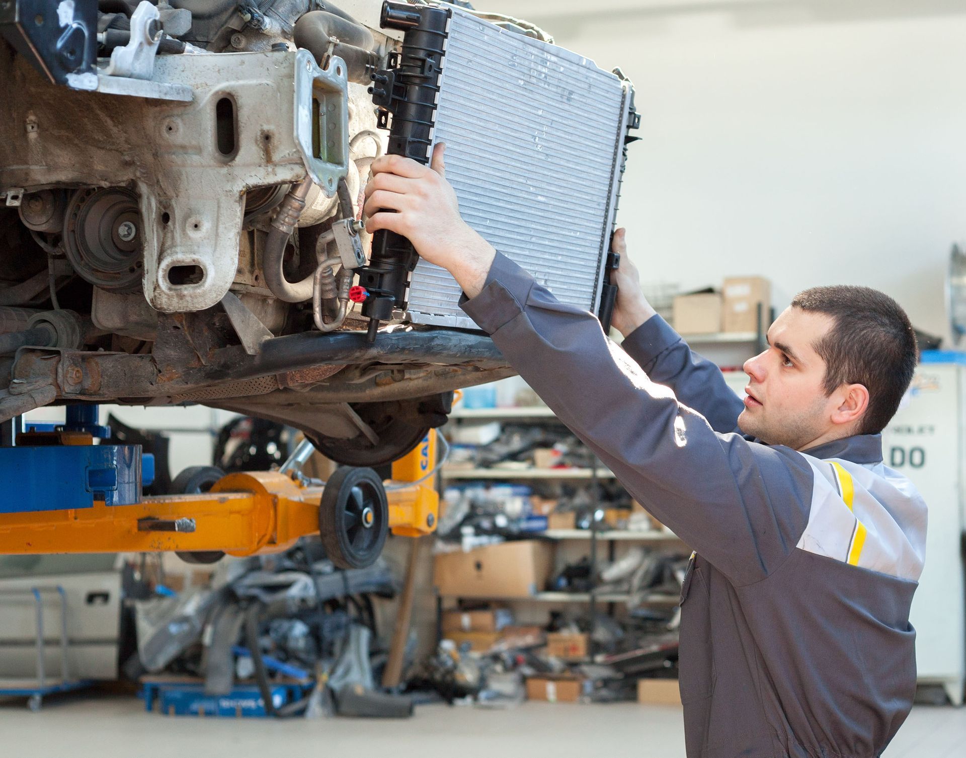 Mechanic inspecting car engine on a lift in an auto repair shop
