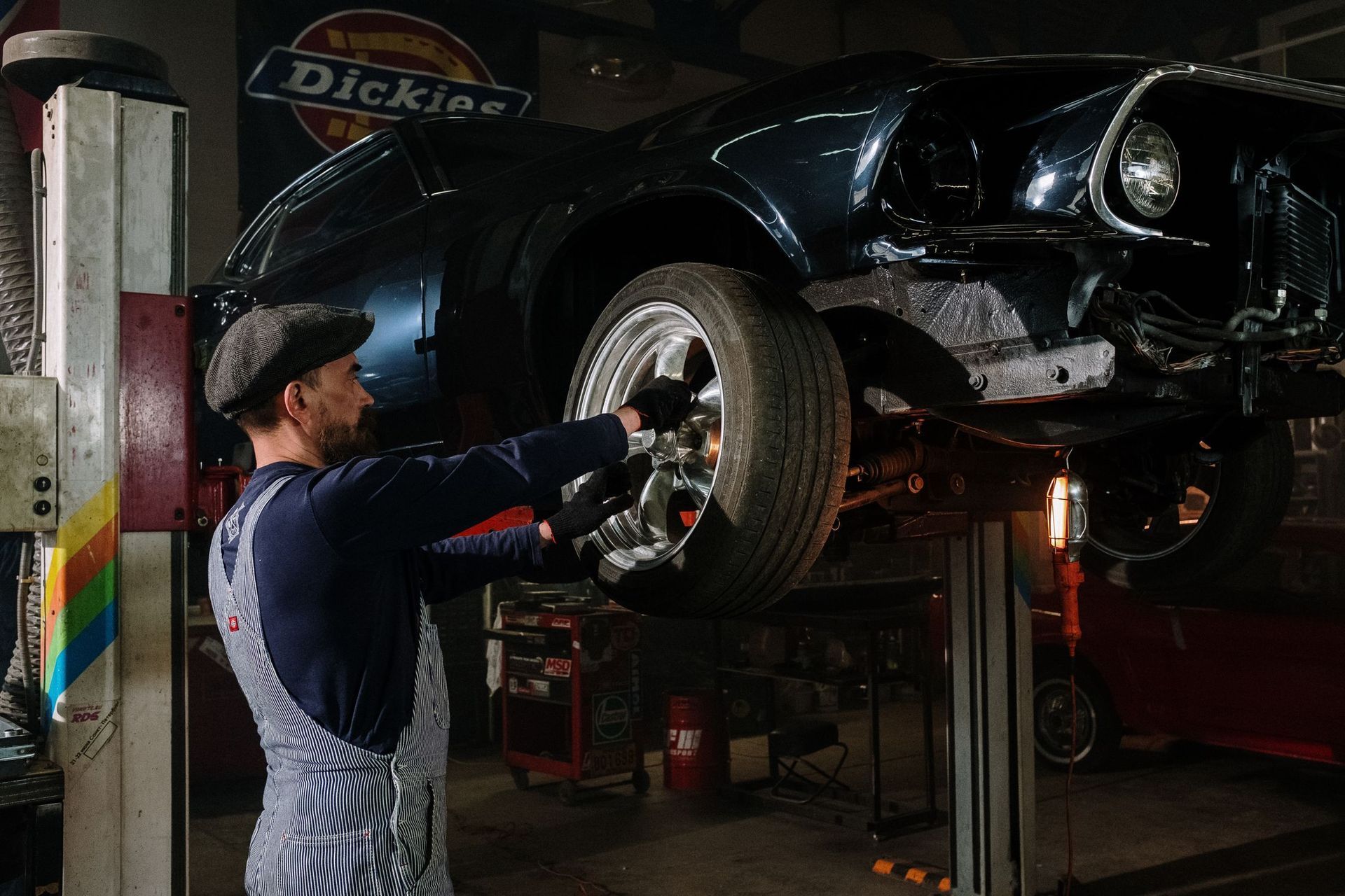 Mechanic working on a black car raised on a lift in an auto repair shop