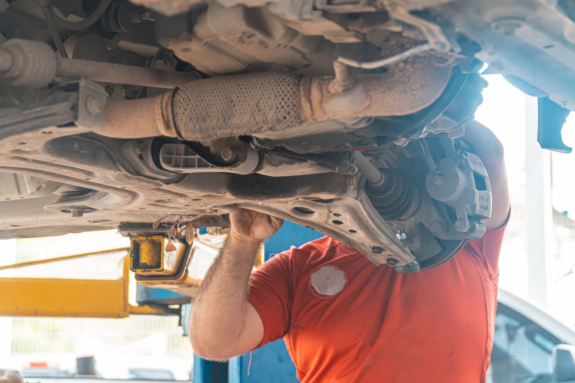Mechanic inspecting the underside of a car on a lift in a garage